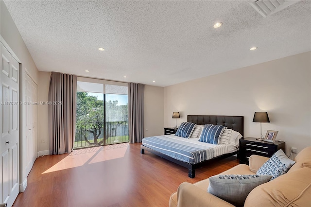 bedroom featuring a textured ceiling, recessed lighting, wood finished floors, and access to exterior