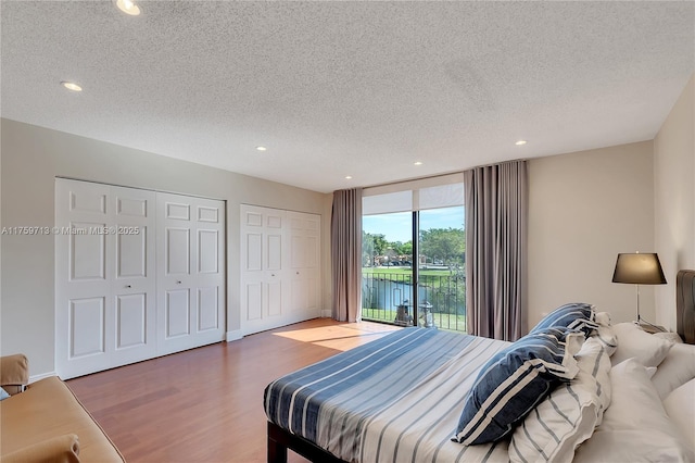 bedroom with multiple closets, access to exterior, recessed lighting, and wood finished floors