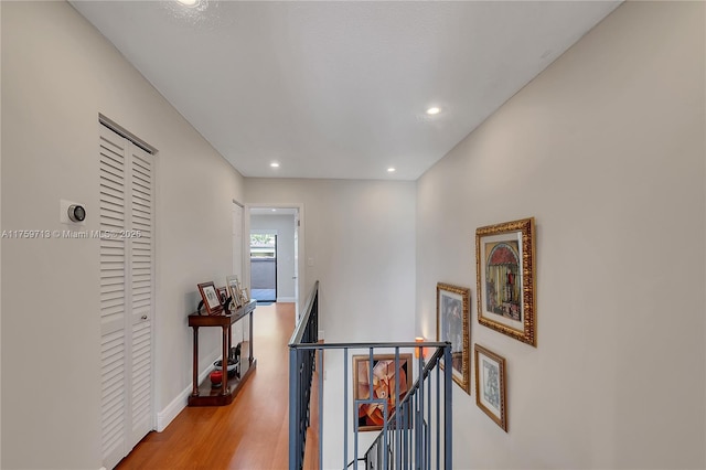 hall with recessed lighting, baseboards, an upstairs landing, and wood finished floors