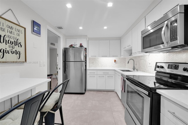 kitchen with stainless steel appliances, light countertops, decorative backsplash, light tile patterned flooring, and a sink