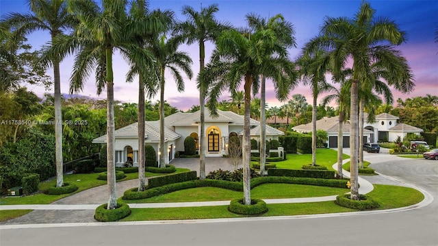 mediterranean / spanish home featuring a front lawn, decorative driveway, and stucco siding