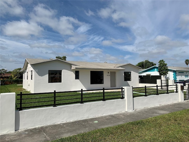 view of front facade with a fenced front yard, a front yard, and stucco siding