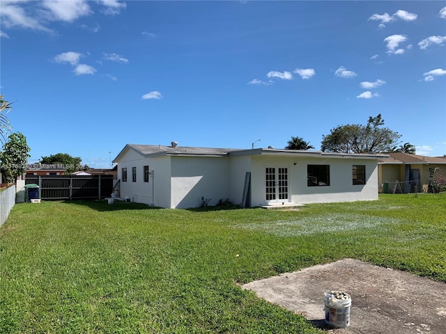 back of property with a lawn, fence, and stucco siding