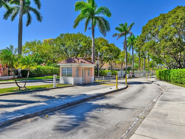 view of road with a gated entry, curbs, and sidewalks