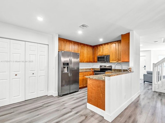 kitchen with light wood finished floors, visible vents, brown cabinets, and stainless steel appliances