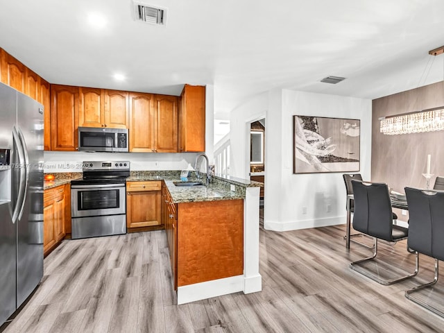 kitchen featuring visible vents, light wood-type flooring, brown cabinetry, stainless steel appliances, and a sink