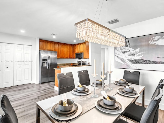 dining area featuring recessed lighting, visible vents, light wood-style flooring, and a chandelier