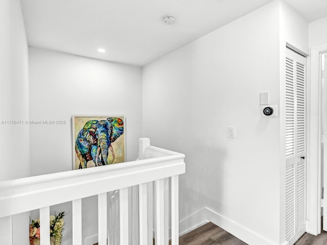 hallway with wood finished floors, an upstairs landing, and baseboards