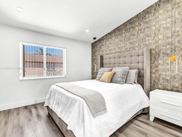 bedroom featuring recessed lighting, baseboards, wood finished floors, and an accent wall