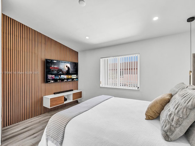 bedroom with recessed lighting, wooden walls, and wood finished floors