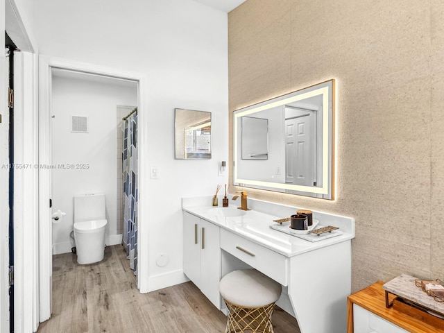 bathroom featuring vanity, wood finished floors, visible vents, baseboards, and toilet