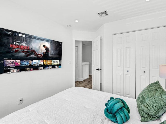 bedroom with a closet, visible vents, recessed lighting, and wood finished floors