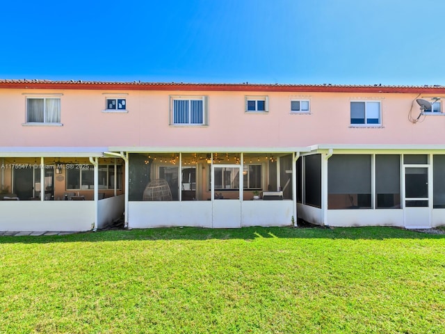 rear view of house with a lawn and a sunroom