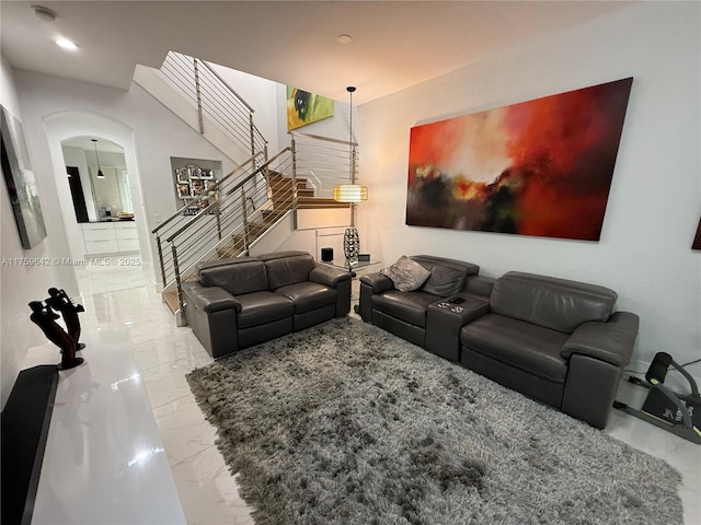 living area with stairway, arched walkways, and marble finish floor