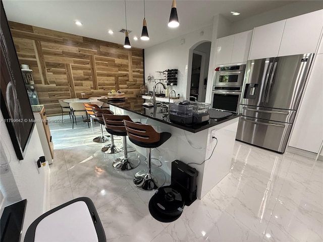 kitchen featuring dark countertops, stainless steel appliances, wooden walls, and marble finish floor