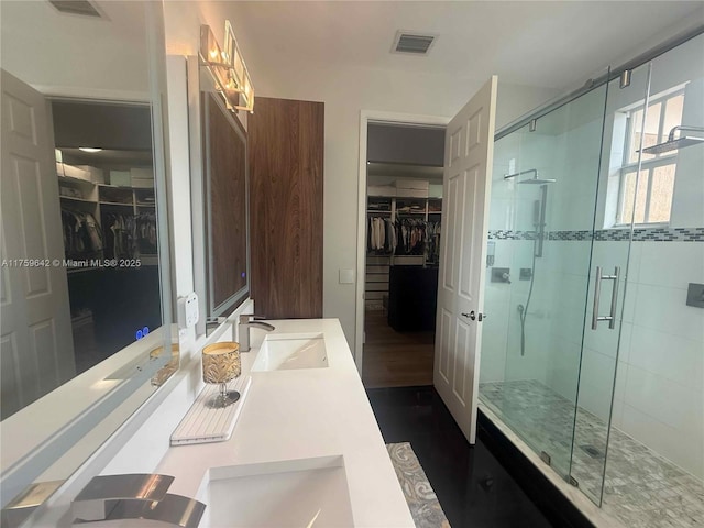 bathroom with double vanity, visible vents, a stall shower, and a sink