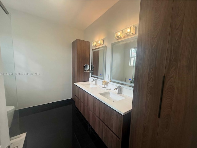 full bath with double vanity, toilet, baseboards, and a sink