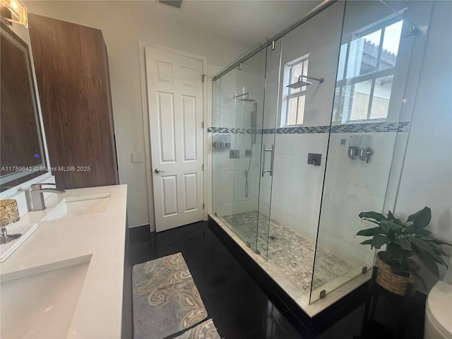 bathroom featuring a shower stall, toilet, double vanity, and a sink