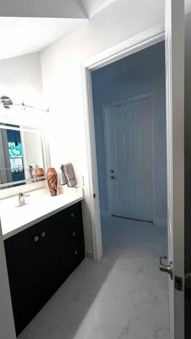 bathroom featuring vanity, lofted ceiling, and marble finish floor