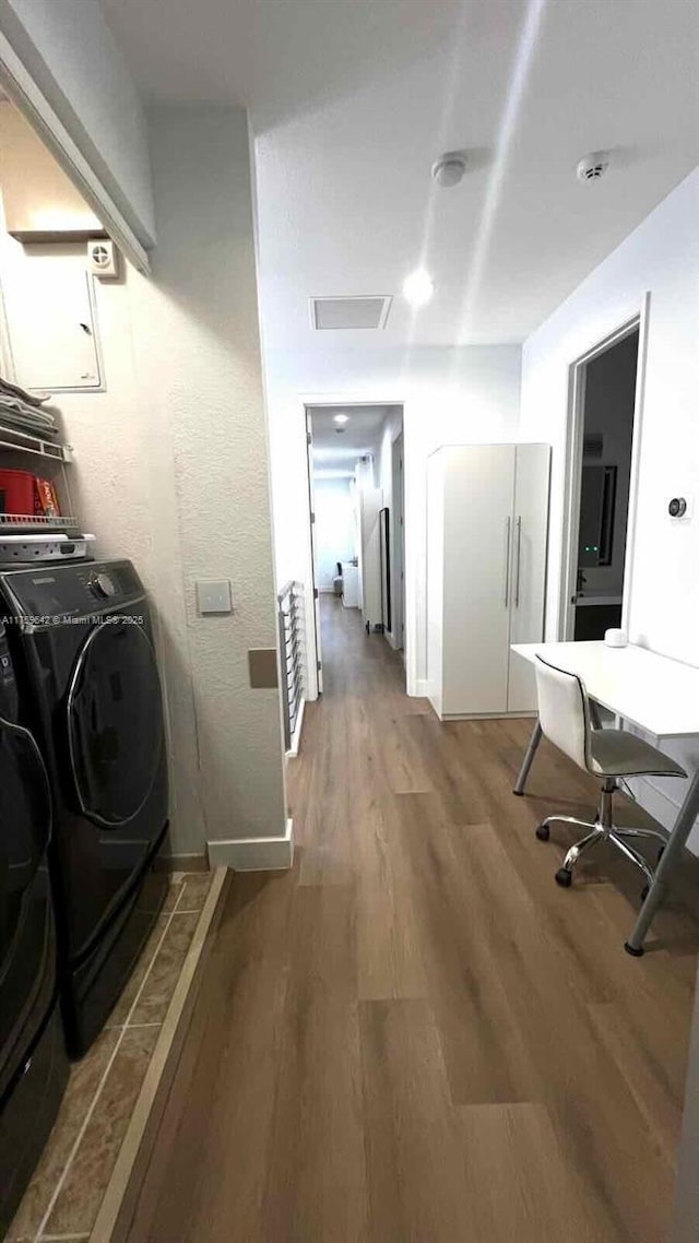 laundry room with laundry area, washing machine and dryer, baseboards, and wood finished floors