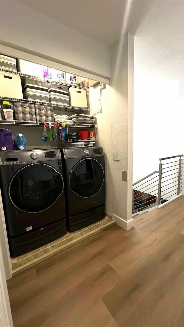 laundry area featuring laundry area, washer and dryer, baseboards, and wood finished floors