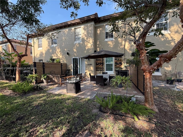 back of house featuring stucco siding, a patio, a fire pit, and fence