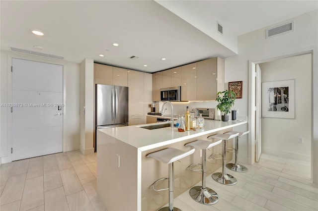 kitchen with visible vents, modern cabinets, appliances with stainless steel finishes, a peninsula, and a sink