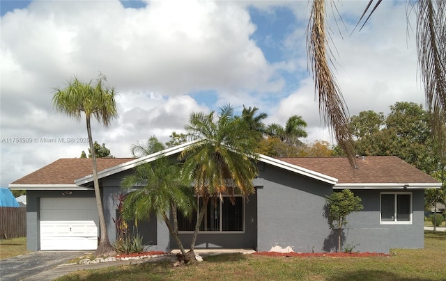 view of front of house featuring a front yard, a shingled roof, stucco siding, a garage, and aphalt driveway