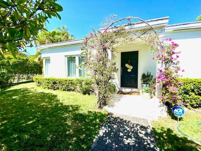 doorway to property featuring a lawn and stucco siding