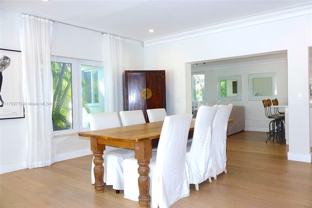 dining room featuring baseboards, light wood-style flooring, ornamental molding, and a wealth of natural light