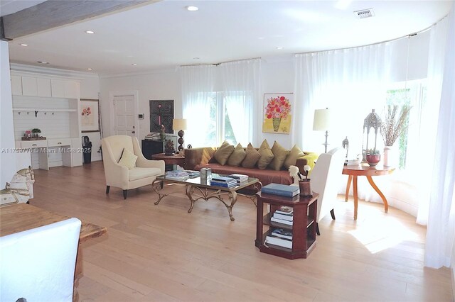 living room with light wood-type flooring, visible vents, ornamental molding, and recessed lighting