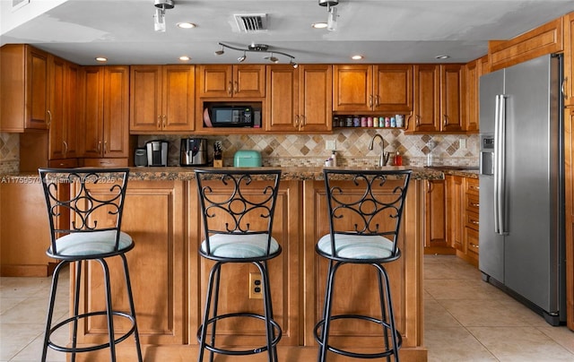 kitchen featuring visible vents, light tile patterned flooring, stainless steel fridge, black microwave, and tasteful backsplash