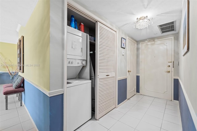 washroom featuring light tile patterned floors, visible vents, laundry area, and stacked washing maching and dryer