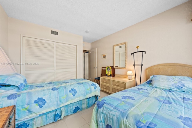 tiled bedroom featuring a closet, visible vents, and a textured ceiling