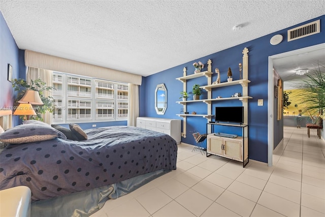 bedroom featuring light tile patterned floors, visible vents, and a textured ceiling