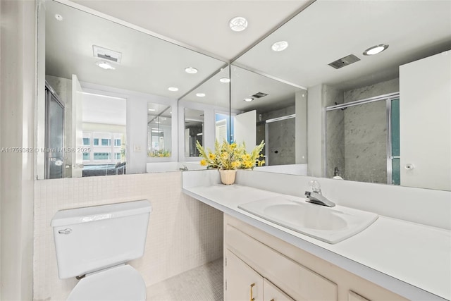 bathroom featuring tile walls, toilet, recessed lighting, a shower with shower door, and vanity