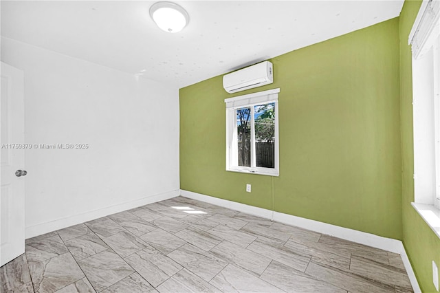 spare room with a wall mounted air conditioner and baseboards