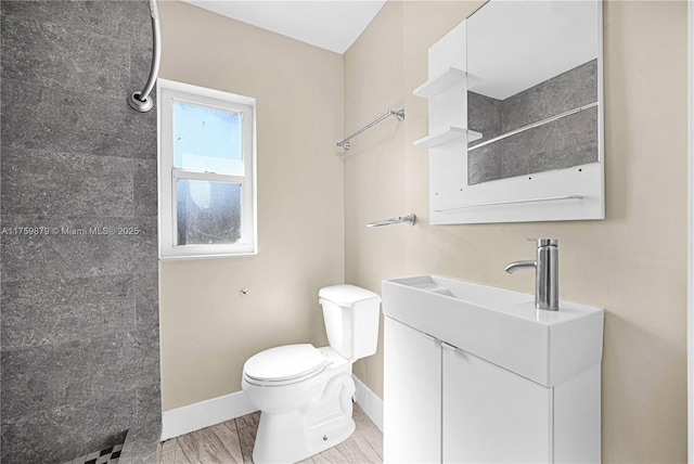 bathroom featuring vanity, toilet, baseboards, and tiled shower