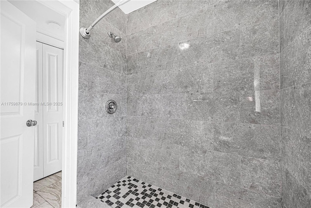 bathroom featuring marble finish floor and a tile shower