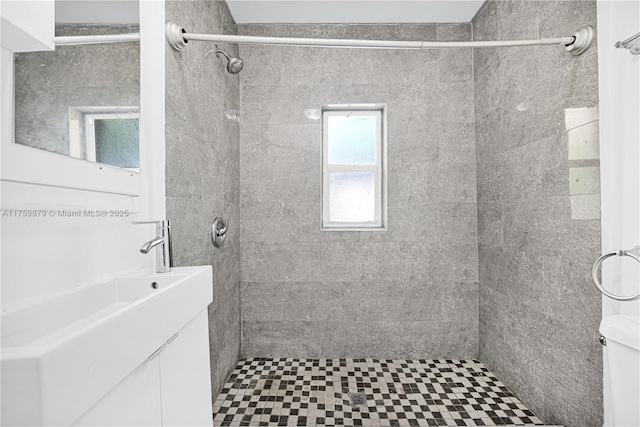 full bathroom featuring tiled shower and vanity