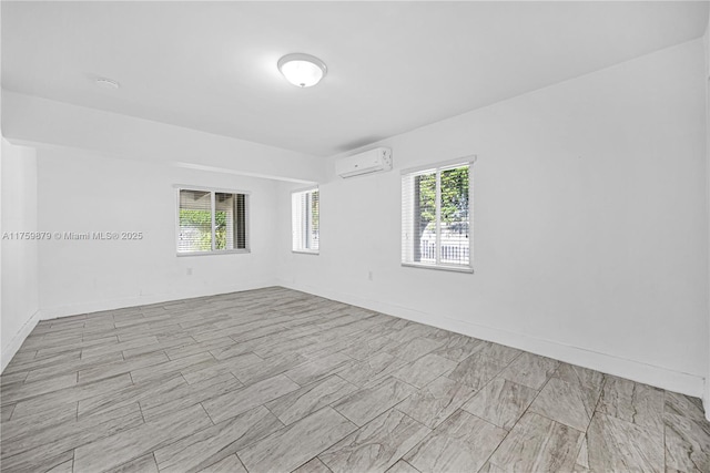 spare room with a wealth of natural light, baseboards, and a wall mounted air conditioner