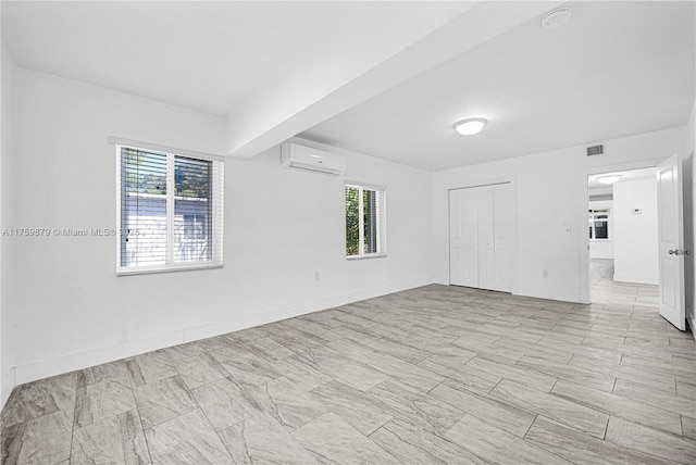 unfurnished room with visible vents, an AC wall unit, and baseboards