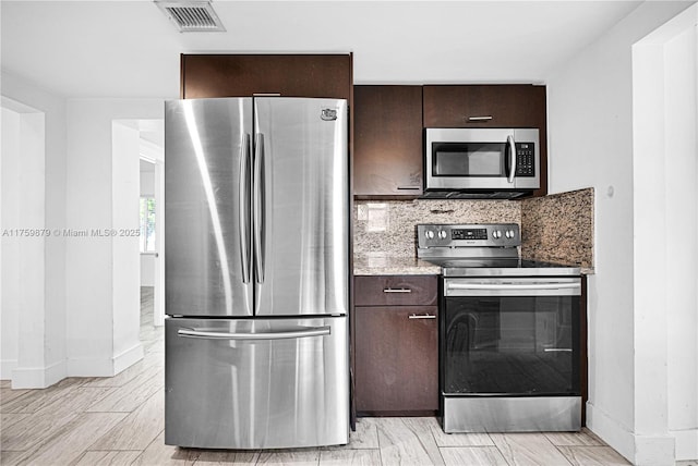 kitchen featuring visible vents, stainless steel appliances, dark brown cabinetry, light countertops, and backsplash