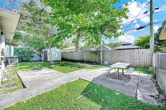 view of yard featuring a storage unit, an outbuilding, a fenced backyard, and a patio area