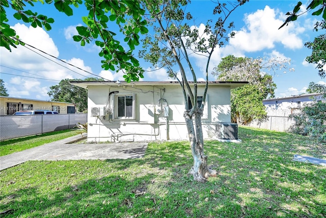 rear view of property featuring a patio area, a yard, fence, and stucco siding