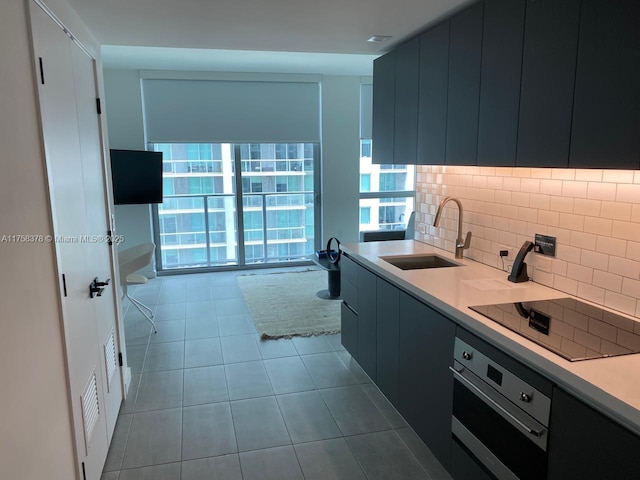 kitchen with oven, tile patterned floors, a sink, decorative backsplash, and black electric stovetop