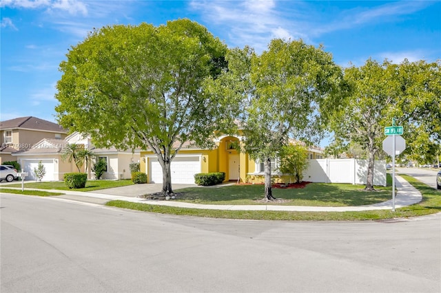 view of front of property with stucco siding, a front lawn, fence, concrete driveway, and an attached garage