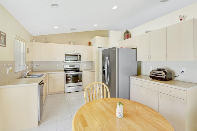 kitchen featuring lofted ceiling, light tile patterned flooring, a sink, light countertops, and appliances with stainless steel finishes