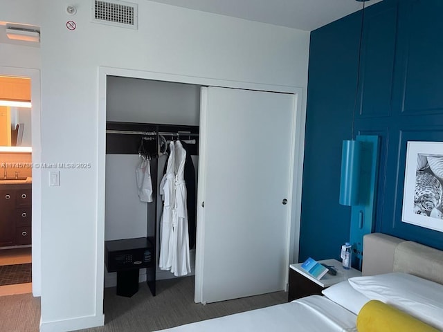 carpeted bedroom with visible vents, a closet, and a sink
