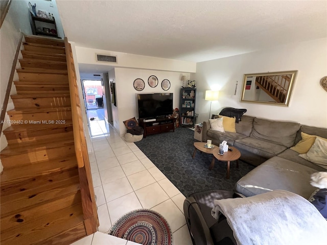 living room featuring stairs, visible vents, and tile patterned floors